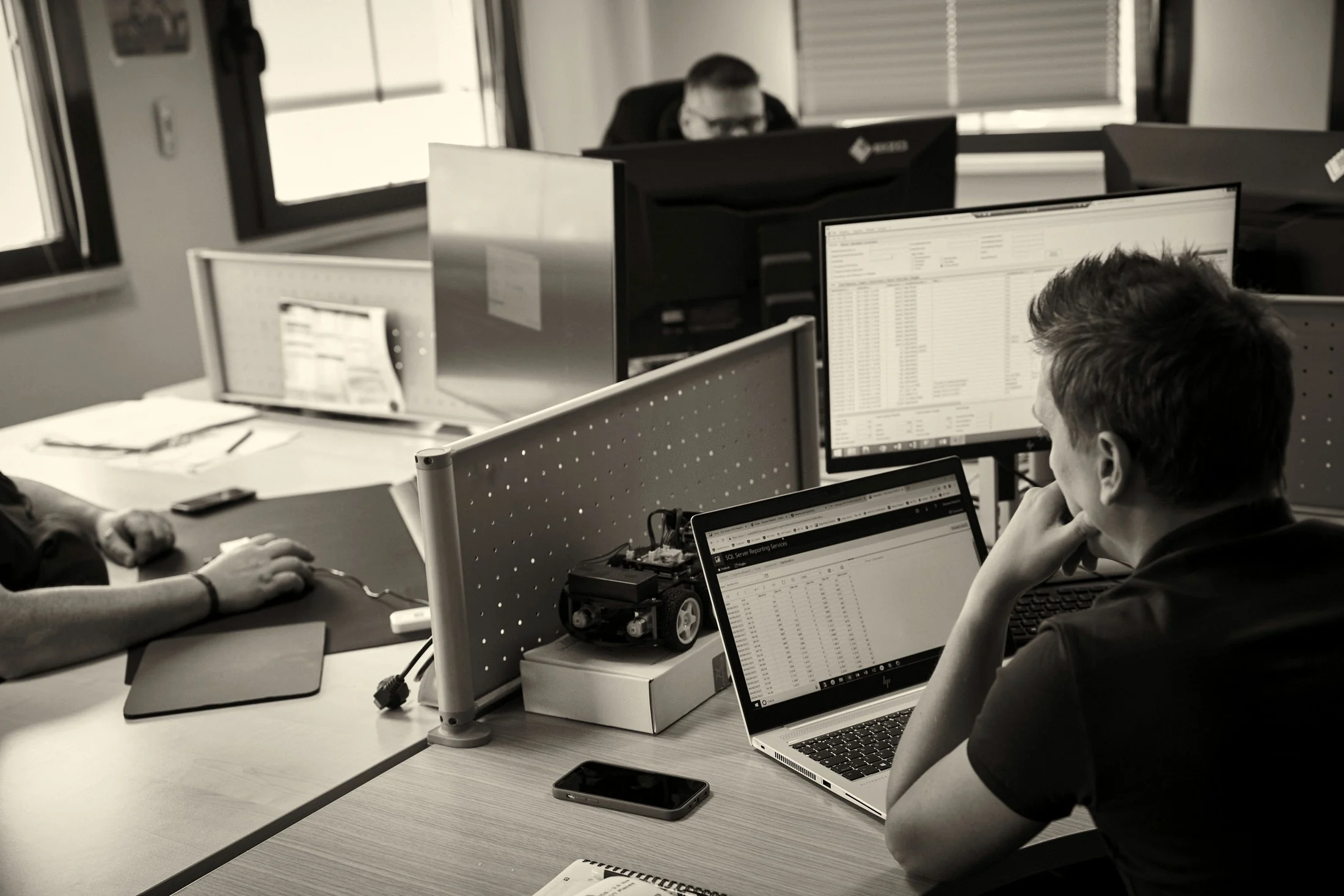 Postazione di lavoro con una dashboard di reportistica dati aperta su due monitor e un laptop