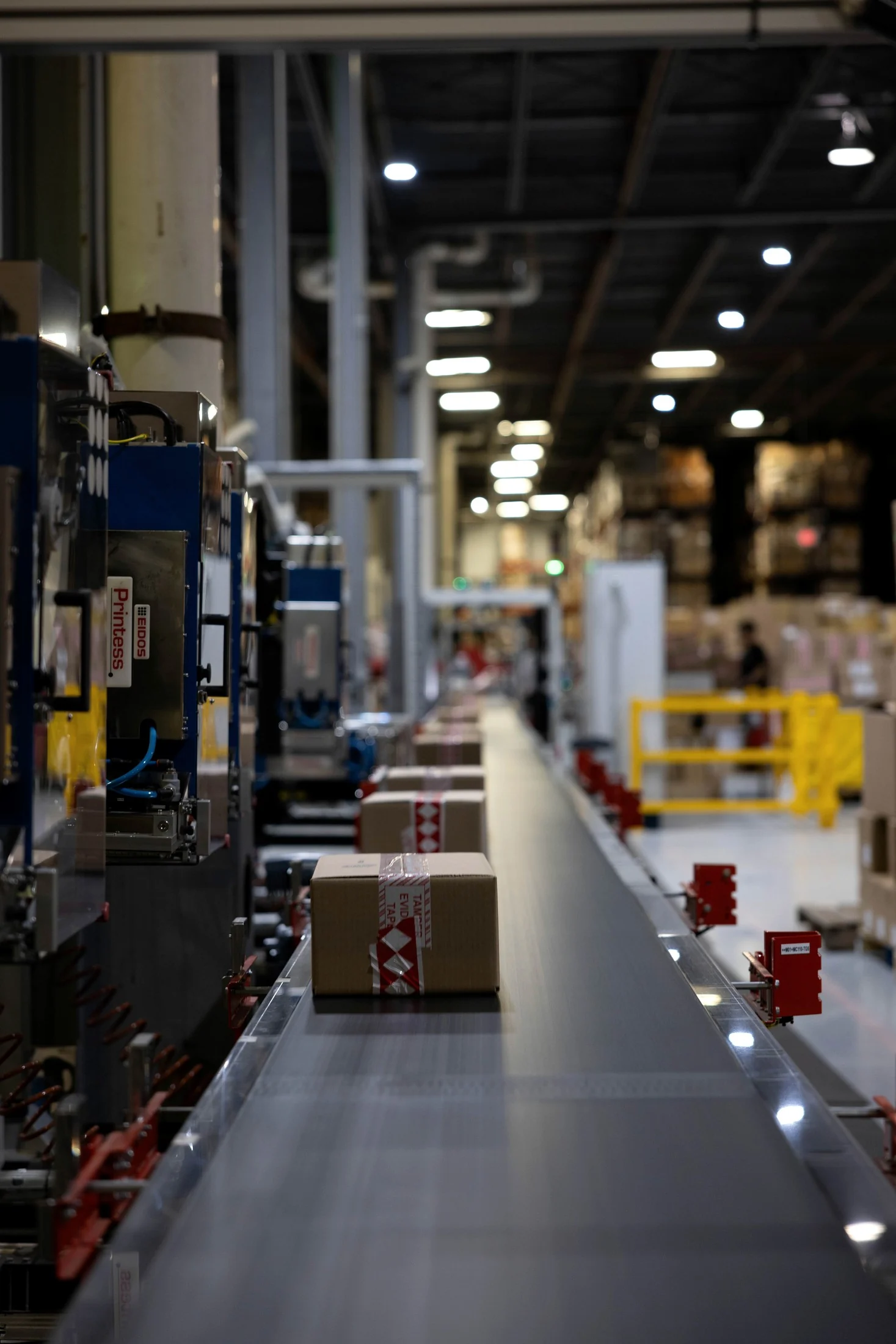 Impianto di etichettatura automatizzato e linea a nastro con nastro adesivo antimanomissione sui colli in uscita, all’interno di un centro di distribuzione Snatt
