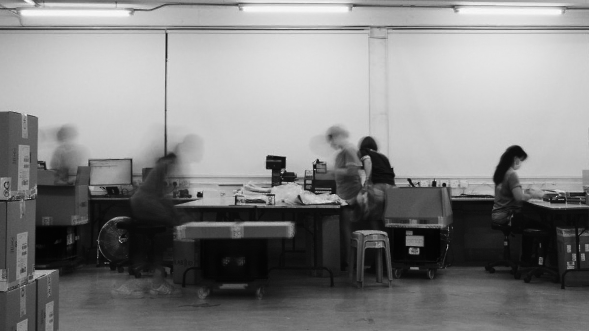 Label workroom with operators at their stations, long exposure in black and white